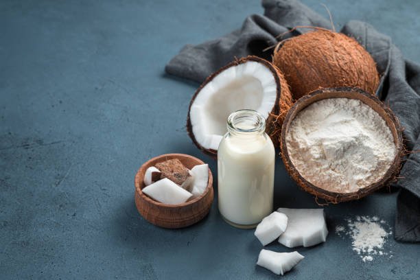 coconut milk, flour and coconuts on a blue background. side view, copy space.